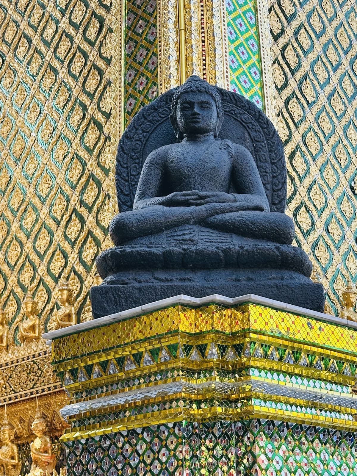 A stone Buddha against glass mosaic