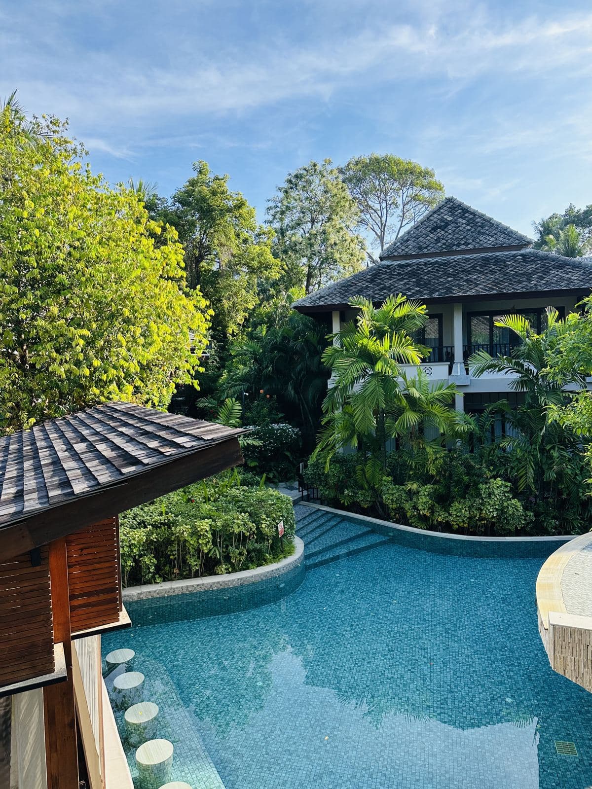 A resort pool winding between villas and gardens