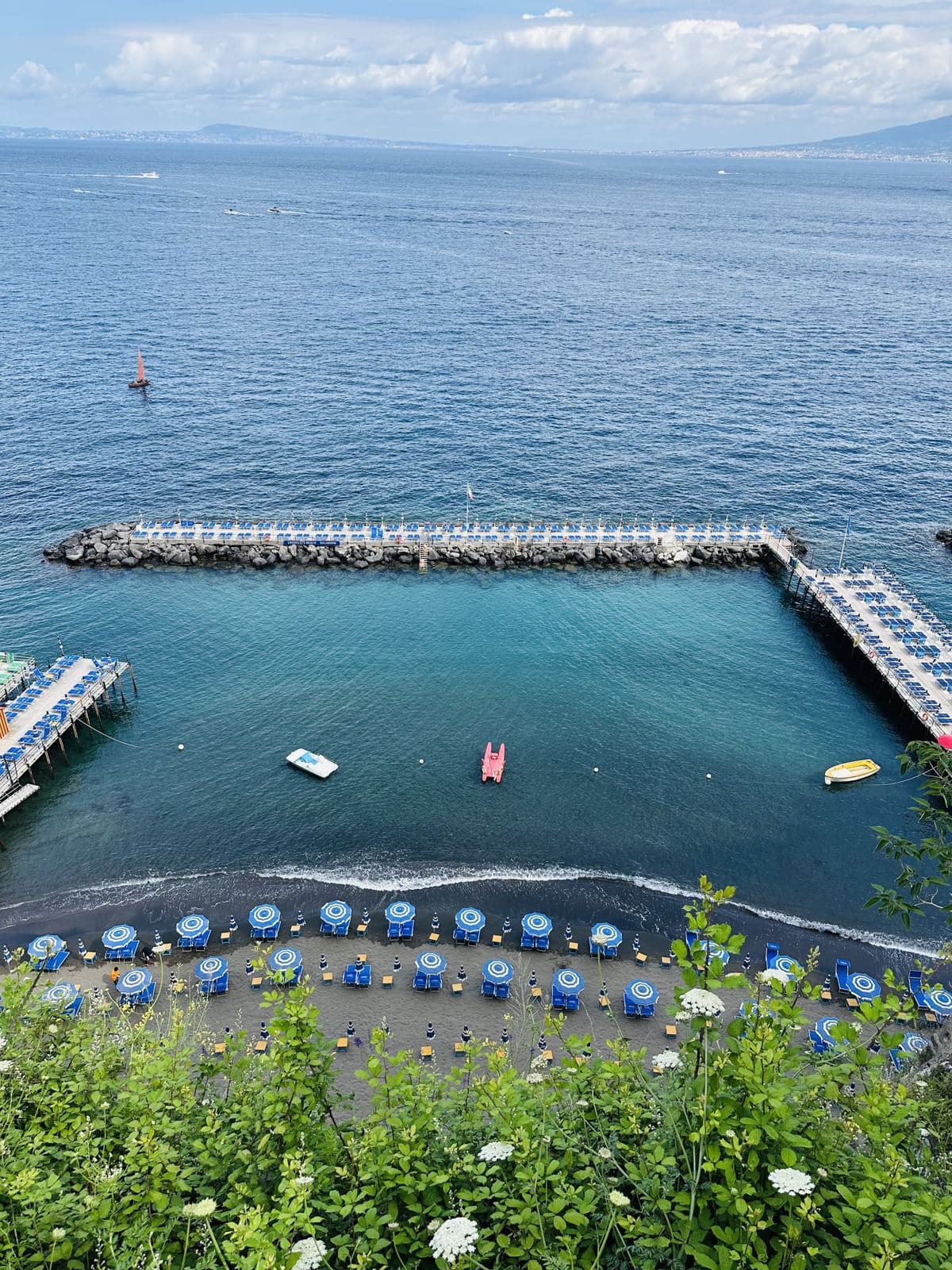 A bathing pier with umbrellas below the cliffs
